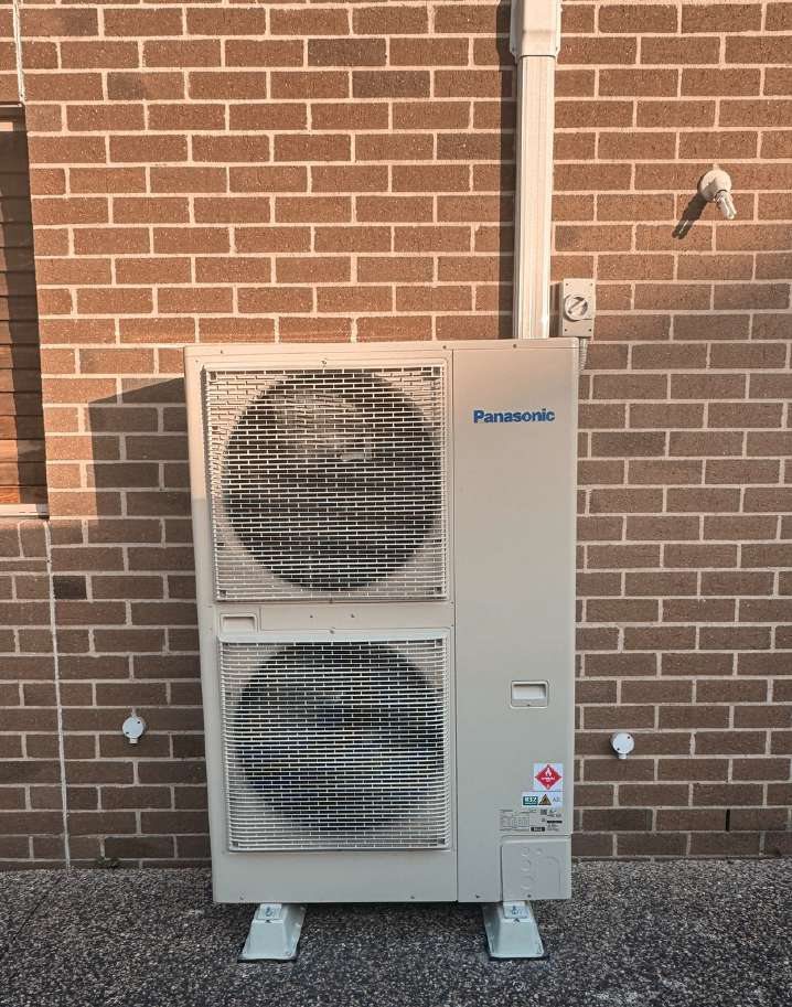 Panasonic ducted outdoor unit on a level base against a brick wall